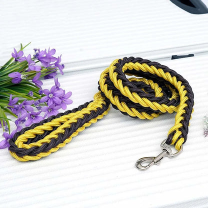 Black and yellow braided dog leash with a clip on a white surface with purple flowers.