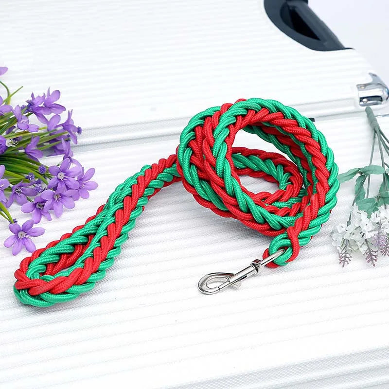 Red and green braided leash with a metal clip on a white surface with flowers.