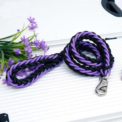 Black and purple braided leash with a metal clip on a white surface with purple flowers.