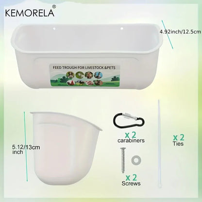 White plastic livestock and pet feed trough with measurement labels, shown with included accessories: two carabiners, two screws, and two ties on a pale green background. The brand KEMORELA appears at top left.
