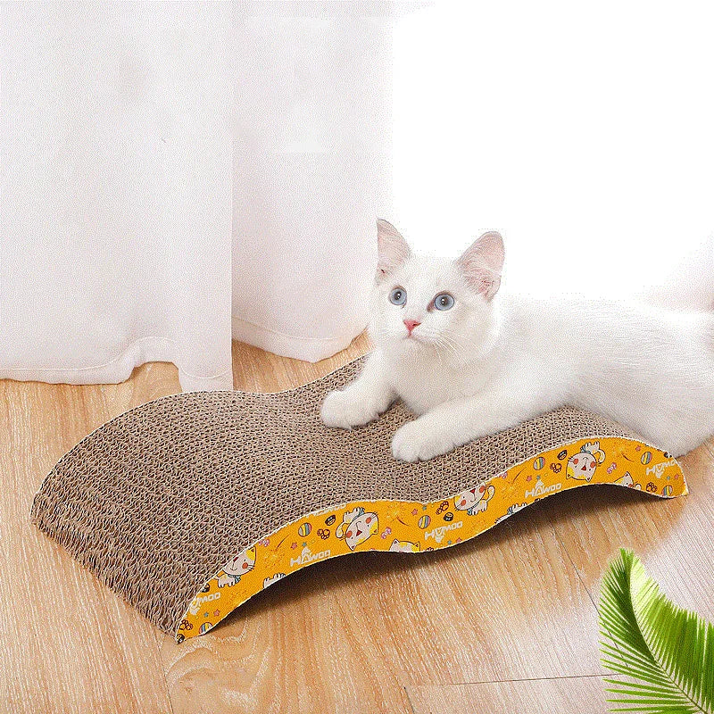 White cat sitting on a floral-patterned cardboard scratcher on a wooden floor.