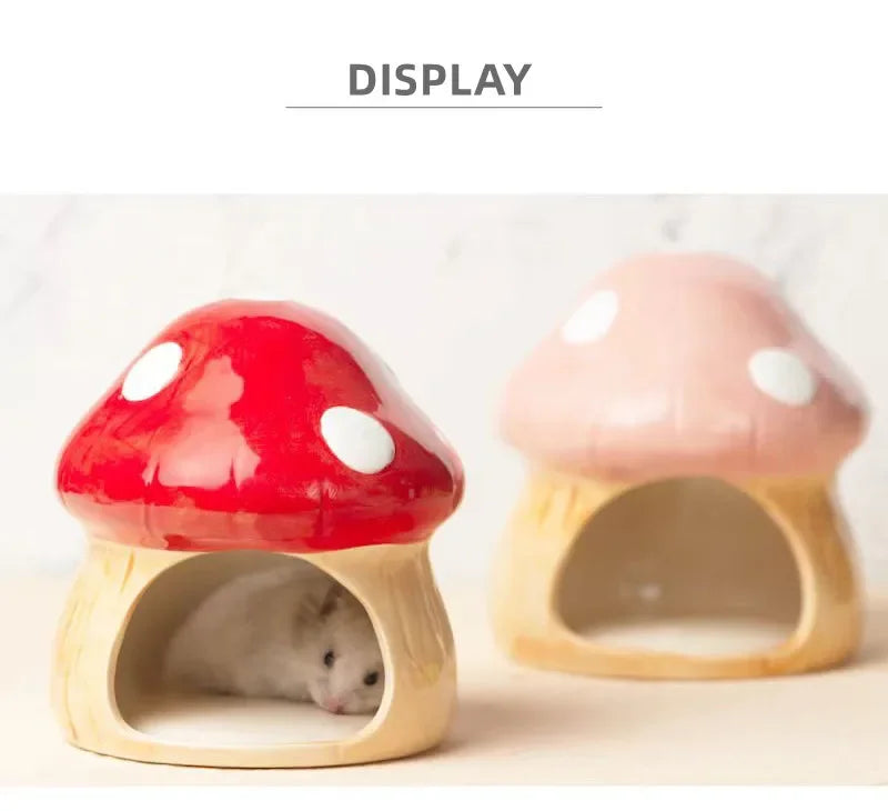 Two mushroom-shaped ceramic hamster houses displayed on a light surface, with one red and one pink house in the foreground and a small white hamster visible inside the red house. The word 'DISPLAY' appears at the top.