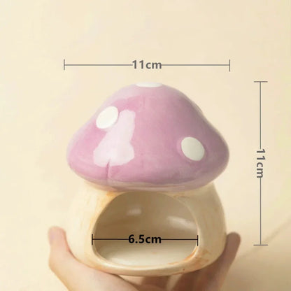 A small mushroom-shaped ceramic pet house with a pink lid and cream base, held in a hand. Black measurement lines and text show dimensions: 11 cm width, 11 cm height, and 6.