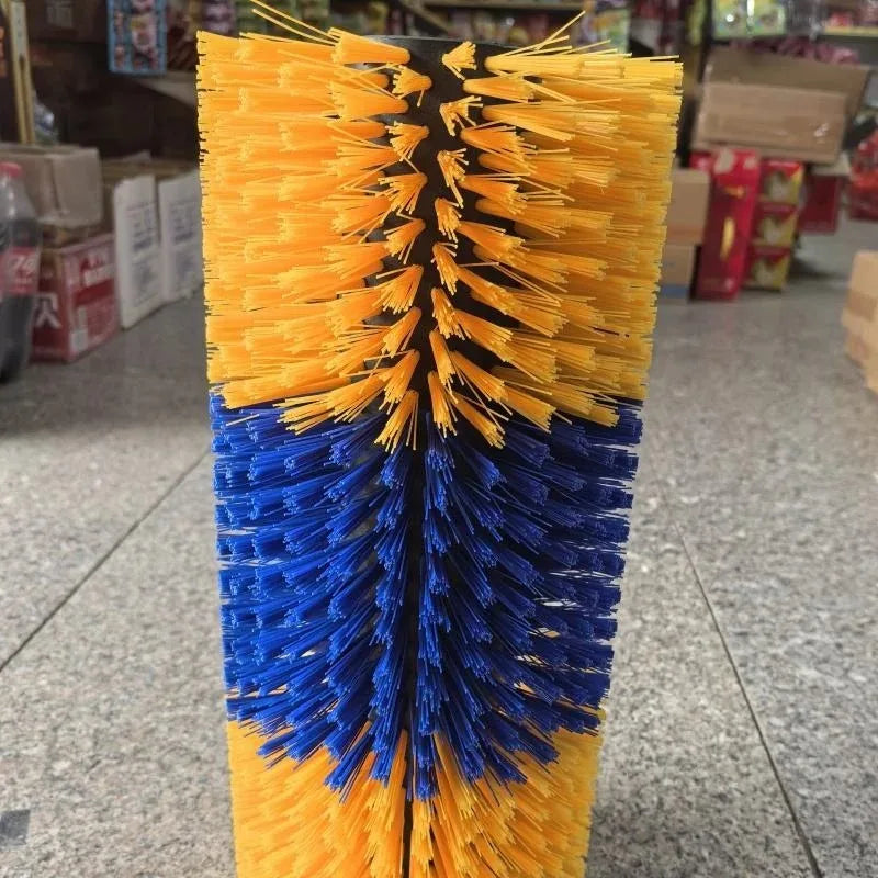 A large industrial automatic car wash brush with yellow and blue bristles, standing upright on a speckled gray floor in a store or warehouse setting.