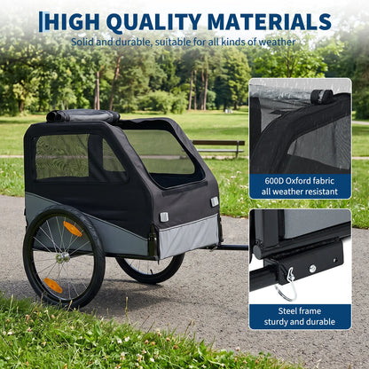 A black and gray bicycle trailer with mesh side windows, shown outdoors on a paved path with grass and trees in the background. Text at the top reads 'HIGH QUALITY MATERIALS' and two inset callouts highlight 600D Oxford fabric weather resistance and a steel frame.