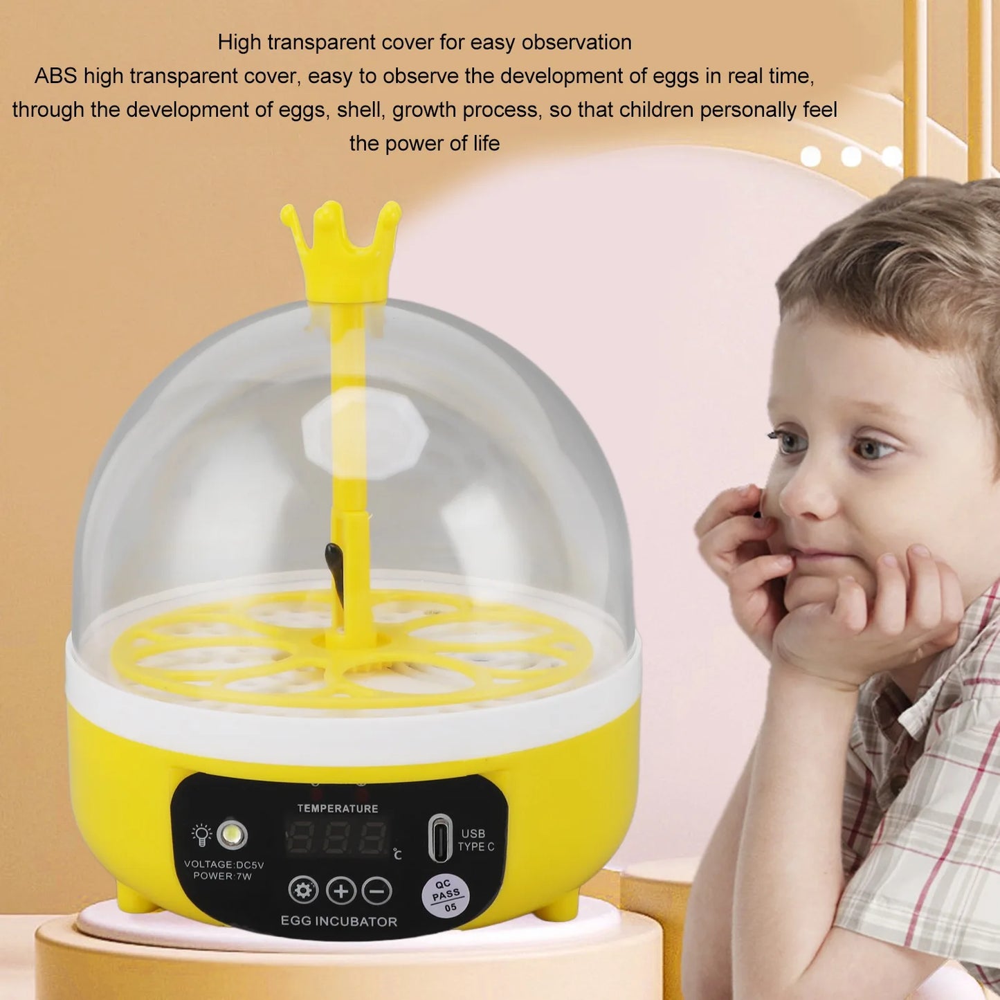 Yellow egg incubator with a transparent dome and a child observing it, on a light pink background.