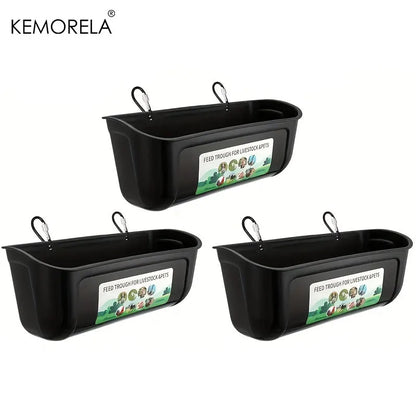 Three black plastic livestock waterers by KEMORELA, arranged in a triangular layout on a white background. Each waterer has a hanging loop at the top and a label on the front that reads 'FEED TROUGH FOR LIVESTOCK WATERS'.