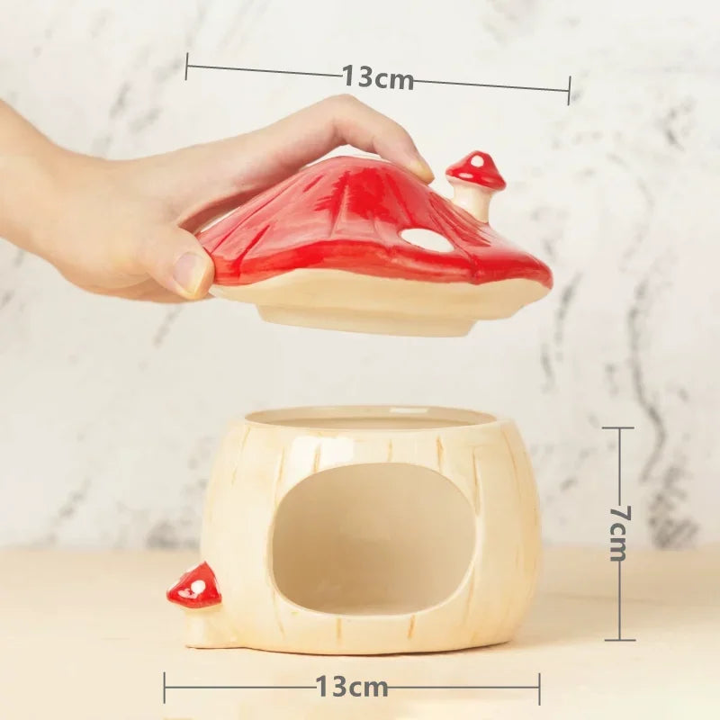 A hand is lifting a red-and-cream mushroom-shaped ceramic lid off of a matching cream mushroom-shaped base, with overlaid dimension lines showing 13 cm width and 7 cm height.