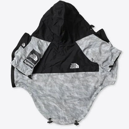 A hooded windbreaker jacket from The North Face, featuring a black upper section and a light gray camouflage patterned lower body and sleeves. The jacket is laid flat on a light gray background, showing the Hypotherm sleeve patch and the brand logo.