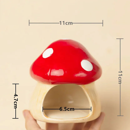 A mushroom-shaped ceramic pet house with a glossy red cap, white spots, and a cream-colored base, held by a hand. Black dimension lines and text overlays show measurements of 11cm width, 11cm height, and 6.