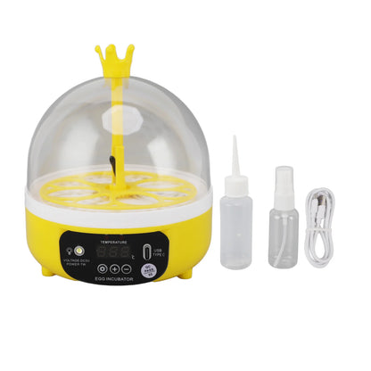 Yellow egg incubator with a crown on top, accompanied by two bottles and a cable on a white background.